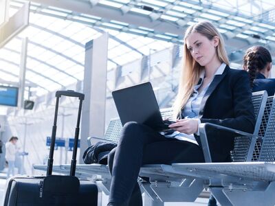 Frau an einer S-Bahn Haltestelle arbeitet auf ihrem Laptop
