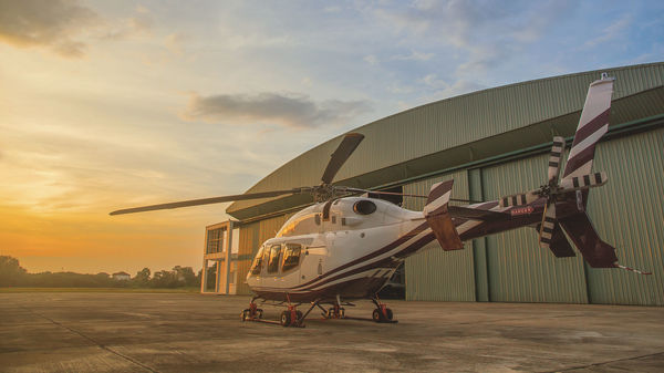 Helikopter vor Hangar bei Sonnenuntergang