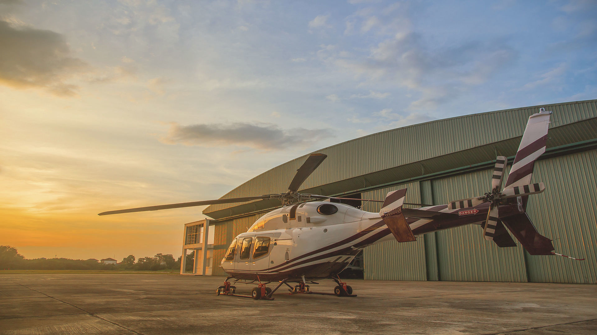 Helikopter vor Hangar bei Sonnenuntergang