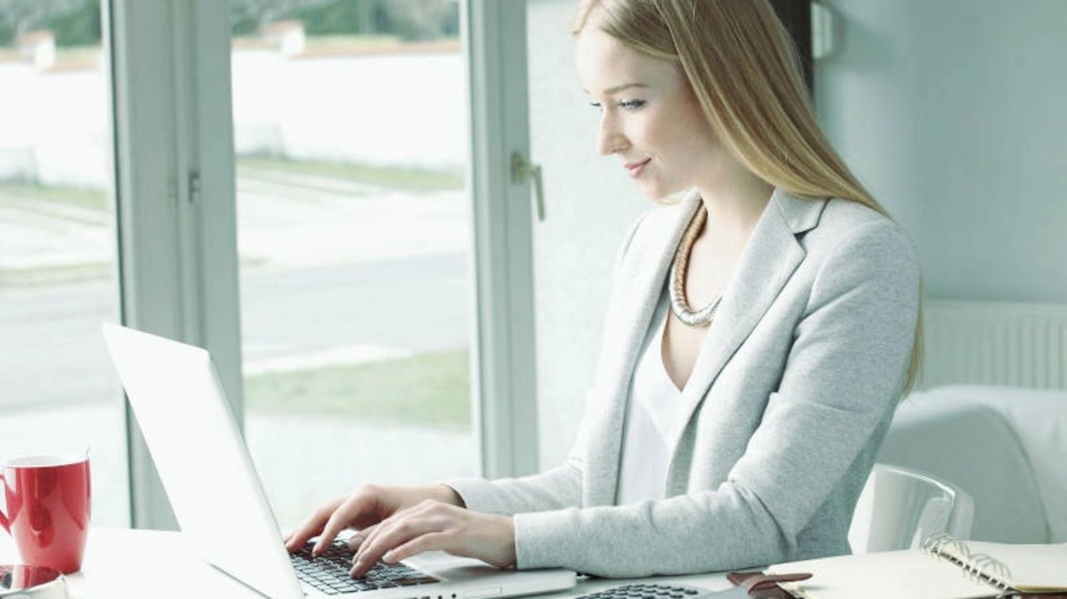 Frau arbeitet am Küchentisch zuhause am Laptop
