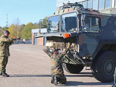 Zwei Männer warten ein Militärfahrzeug