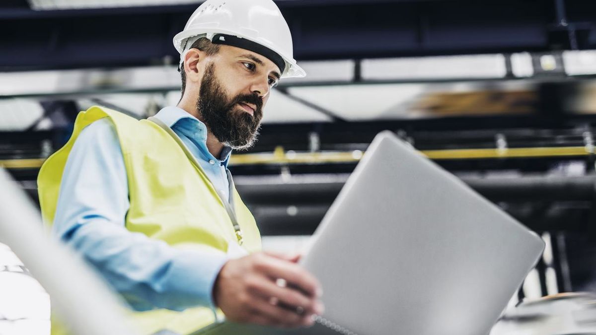 Ein Industrieingenieur mit Laptop in einer Fabrik, bei der Arbeit.