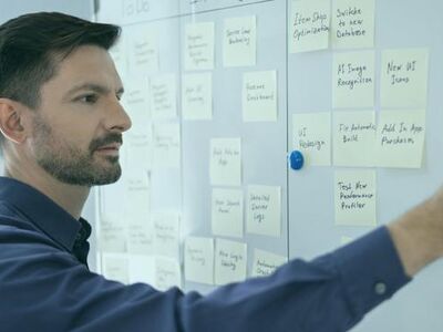 Ein Mann steht vor einem Whiteboard mit vielen beschrifteten Post-its